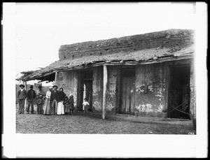 Group of people standing outside a small store on Aliso Street, ca.1880-1882