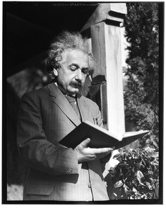 Albert Einstein reading a book outside