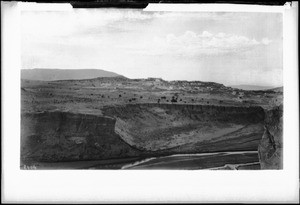 Pueblo of Laguna visible in the distance beyond a large natural basin or canyon, New Mexico, ca.1898