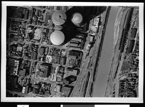 Aerial view of a river passing near storage tanks in Los Angeles County, 1938