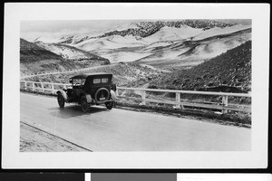 Unmanned automobile on a twisting road through hills, ca.1920