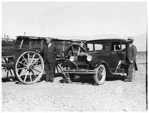 Men standing next to a wagon and automobile