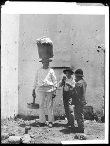 Mexican ice cream and tamale vendor, Nicolas Martinez, standing by two boys who are eating ice cream on Olvera Street, Los Angeles, 1890