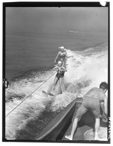 Two women and a man water skiing