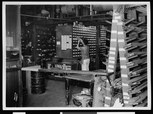 Department of Public Works employee reaching into a drawer in room filled with building supplies