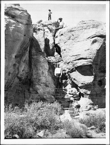 Three men climbing the foot trail to the top of the mesa of the Hopi (Moki) pueblo of Mishongnovi (Mashongnave), Arizona, ca.1898