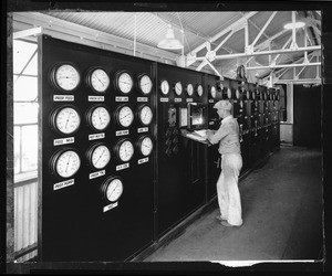 Man looking at meters in the propane control room at the Triton Motor Oil refinery, 1934