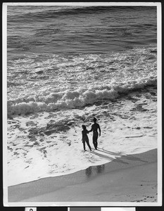 Man and woman walking into surf on a shore