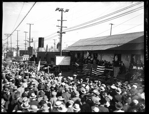 Crowd of spectators gathered outside a building decorated with American flags