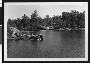 Man standing on boulders in Bartlett's Cedar Lake, ca.1950