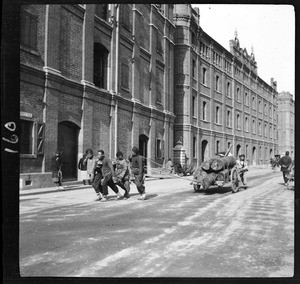 Four men dragging a cart loaded with logs, China