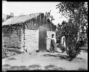 Exterior of a Palm Springs adobe, showing two Indians in front, ca.1934