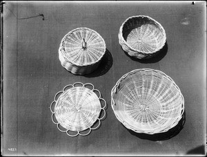 Four Indian baskets displayed against a cloth backdrop, ca.1900