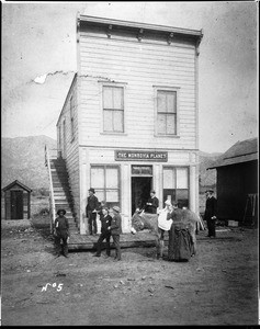 Exterior view of the Monrovia Planet newspaper office building in Monrovia, with hills visible in the distance, ca.1890-1899