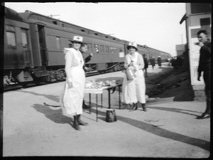 Two Red Cross ladies serving coffee to soldiers at a train station, 1910-1920