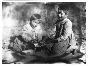 Two Havasupai Indian children, the daughters of Chickapanagie's, enjoy a mellon, ca.1900