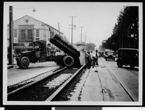 Asphalt being dumped between railroad tracks by dump truck