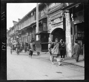 Two men carrying a funerial coach in China, ca.1900