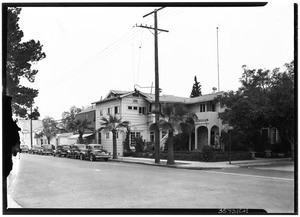 Row of automobiles parked outside a strip of houses by an intersection