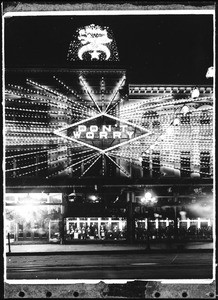 Exterior view of the Broadway Department Store at night, showing lit signs