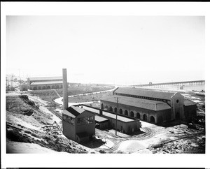 Exterior view of the Hyperion Screening Plant, showing a tall smokestack, ca.1935