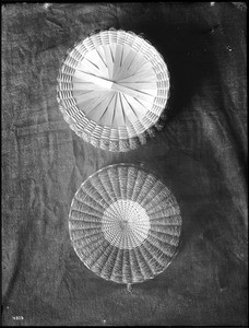 Two Indian baskets displayed against a cloth backdrop, ca.1900