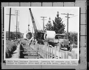 Crane lowering a pipe into a trench on Yosemite Drive in the Eagle Rock Drainage District, September 27, 1936