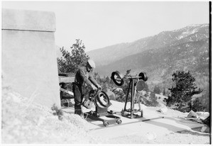 Man setting up telescope equipment on a hill