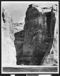 View of cliffs showing a parked automobile or wagon at their base, ca.1900