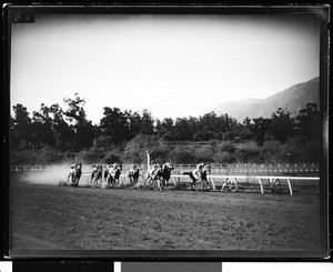 Horses rounding a turn at an unidentified race track