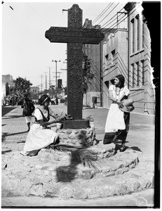 Two women near a large cross-shaped monument