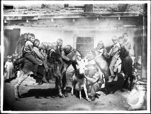 Dr. George Wharton James with a group of Hopi Indian children and burros in the village of Shonguapavi, ca.1901-1907