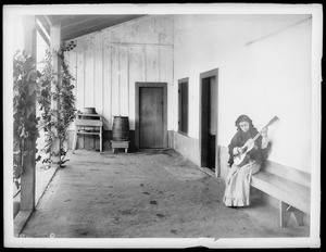 Girl playing guitar on the veranda of Camulos Ranch, California