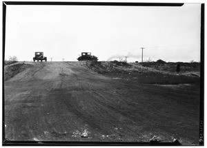 Two automobiles parked on a ridge near an unpaved road