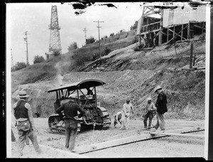 Seven men working with a tractor