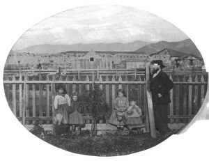 A man and four little girls leaning against a picket fence, near Mission San Luis Obispo, ca.1865