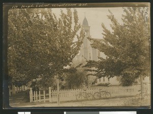 Bicycles parked in front of a tree-obscured high school in Woodland, 1900-1940