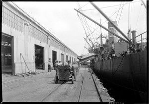 Workers loading steel onto a tractor in Los Angeles harbor