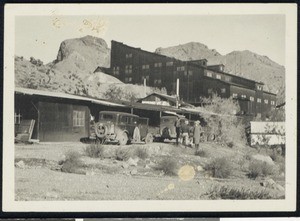 Group of men standing next to two automobiles outside of what appears to be a mining warehouse, ca.1900