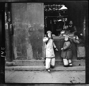 Three children buying candy from a vendor in China, ca.1900