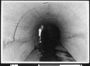 Man standing in a storm drain, ca.1930