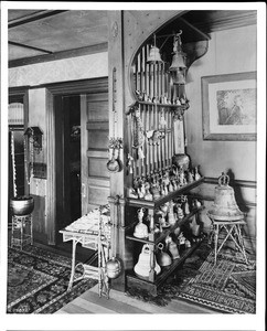 Interior of Mrs. Robert Burdette's home in Pasadena, showing a bell collection, ca.1908