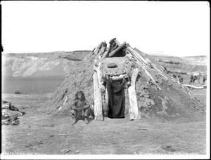 Navajo man sitting in front of his hogan, ca.1900