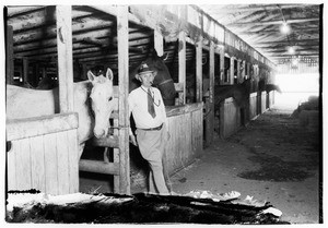 Man standing with a horse in unidentified stables