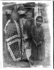 Three Havasupai Indians, the woman Pana-ma-hi-ta, her son, and Waluthama's daughter, in front of a "Hawa" or dwelling, ca.1899