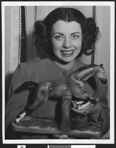 Close-up of a woman with a ceramic horse, ca.1950