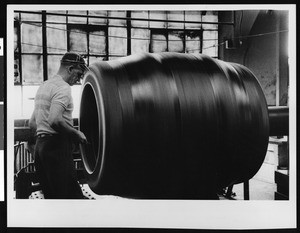 Factory worker making a large tire, ca.1950