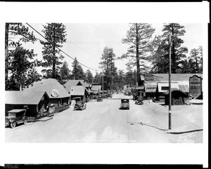 View of Pine Knot Boulevard in Big Bear Lake Village, showing cabins, shops, and automobiles, ca.1920