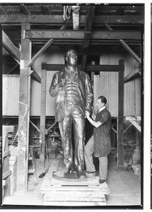 Man creating a bronze statue of a man in a factory