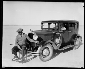 Golfer seated on the front bumper of an automobile